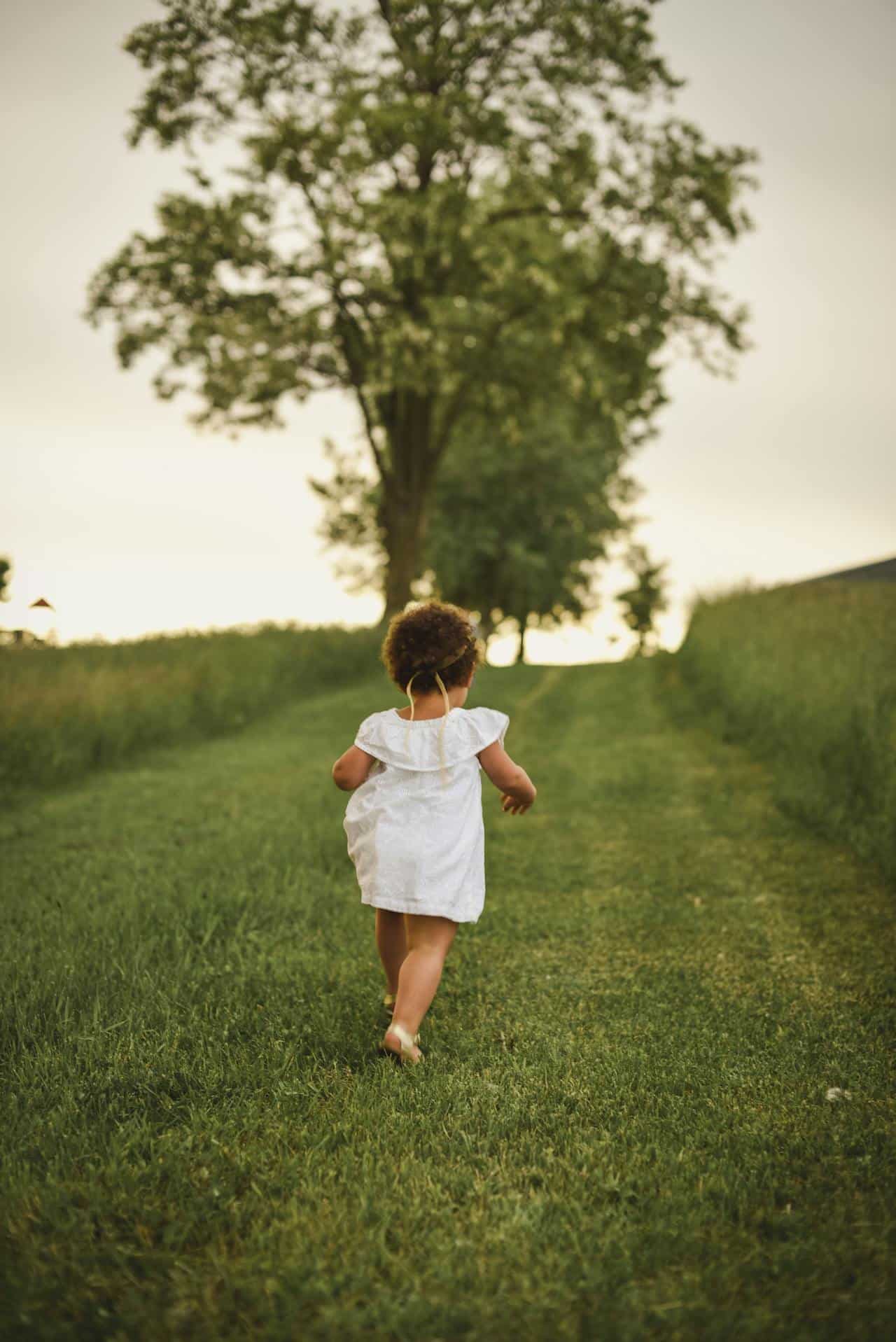 Małe dziecko biegnące po trawie